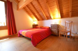 a bedroom with a bed and a chair and a window at Chalet Silene in Le Bourg d'oisans