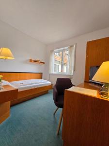 a bedroom with a bed and a desk and a chair at Hotel Samson in Beckum