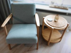 ein blauer Stuhl neben einem kleinen Tisch mit einer Schüssel darauf in der Unterkunft Duhnentraum direkt am Sandstrand, Zentrum, Balkon, Meerblick, Parkplatz, Aufzug, Wlan Netflix uvm in Cuxhaven