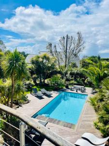 a swimming pool in a yard with chairs and trees at Villa rospico, 200m de la plage avec piscine in Névez