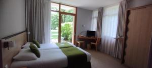 um quarto de hotel com uma cama e uma grande janela em Hôtel Les Esclargies em Rocamadour