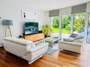 a living room with two couches and a flat screen tv at Villa rospico, 200m de la plage avec piscine in Névez