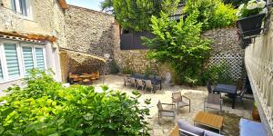 an outdoor patio with chairs and tables and a building at La Belle Maison in Avèze