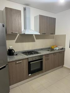 a kitchen with wooden cabinets and a stove top oven at 2 bedroom apartment with sea view and private pool in Sidi Bouqnadel