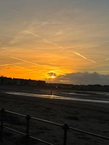 Ruthven في Stevenston: غروب الشمس على الشاطئ مع وجود سياج في المقدمة