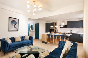 sala de estar con sofás azules y cocina en L'art de Gambetta ConciergerieDameCarcas, en Carcassonne