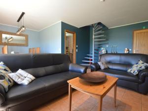 a living room with a black couch and a table at Picture perfect Holiday Home in Sourbrodt with Garden BBQ in Sourbrodt