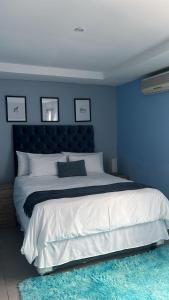 Dormitorio azul con cama grande y pared azul en Mo'Acress Lifestyle, 