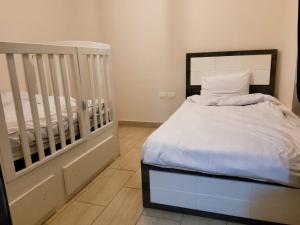 1 dormitorio con cuna y 1 cama con sábanas blancas en Aldau Heights, en Hurghada