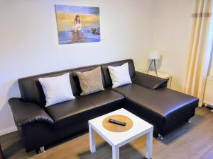 een zwarte leren bank in een woonkamer met een tafel bij Ferienwohnung Schreiberstraße in Wernigerode