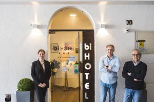 un groupe de trois personnes debout devant une porte dans l'établissement Bi Hotel, à Porto Ercole