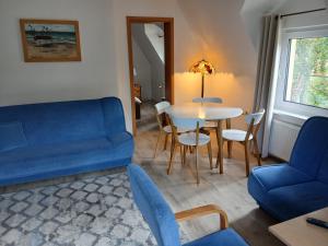 a living room with a blue couch and a table at Przy Lesie Apartamenty Pokoje Parking in Pobierowo