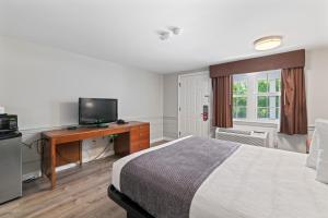 Habitación de hotel con cama y escritorio con TV. en Knight's Inn Boston/Danvers, en Danvers