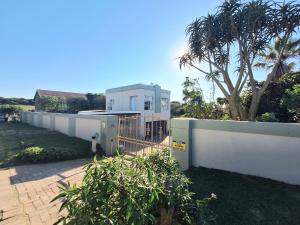 una casa blanca con una valla delante en Sea Breeze Apartments, en Port Alfred