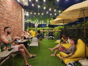 a group of people sitting at tables in a patio at Wayha Hostel Don Mueang Airport in Bangkok