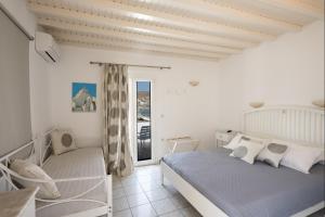 a white bedroom with a bed and a window at Anixi Hotel in Ornos +76 photos