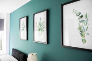 une chambre avec trois photos encadrées sur un mur bleu dans l'établissement Sleeps 4 Monthly Discount WIFI Free Parking, à Borehamwood