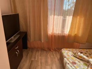 a room with a bed and a television and curtains at Casa Stoian in Costinesti +9 photos