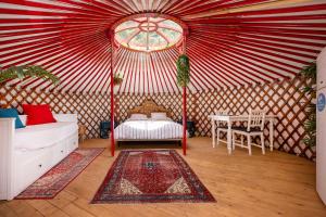 ein rot-weißes Zelt mit einem Bett und einem Tisch in der Unterkunft Casa Rural Alba Montis in Güéjar-Sierra