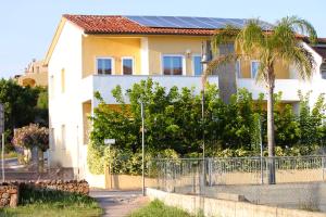 a house with a fence and a palm tree at La Smeralda - Boutique Rooms and Breakfast in Golfo Aranci