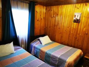 two beds in a room with wooden walls and a window at CASA GUADALUPE SAN FELIPE in San Felipe