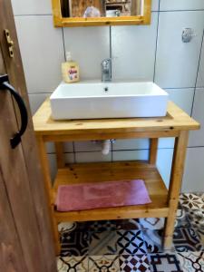 a white sink on a wooden table in a bathroom at Maison adorée in Nea Vrasna