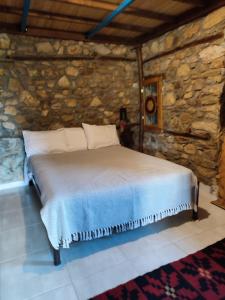 1 dormitorio con 1 cama en una pared de piedra en Maison adorée, en Vrasná
