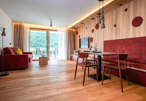 sala de estar con mesa y sofá rojo en Residence & Sportlodges Claudia en Plaus