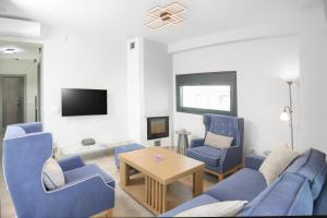 een woonkamer met blauwe stoelen en een tv bij Villa Azul - Pool, Garden, BBQ in Pefkochori