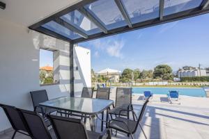 een terras met een tafel en stoelen en een zwembad bij Villa Azul - Pool, Garden, BBQ in Pefkochori +26 foto's