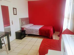 um pequeno quarto com uma cama com uma parede vermelha em LE CEDRE em Saint-Denis