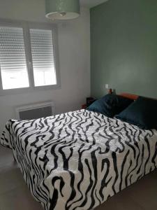 a zebra print bed in a bedroom with two windows at Maison charmante à Rivesaltes, jardin clôturé in Rivesaltes +5 photos