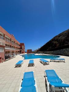 una piscina con sedie a sdraio blu accanto a un edificio di APARTAMENTO ANA a Costa Calma