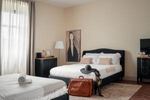 ein Schlafzimmer mit zwei Betten mit Hut und Koffer in der Unterkunft Villa Erbaia Relais de Charme in Barberino di Mugello