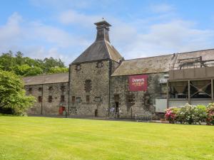 a large stone building with a grass field at Oakbank Mews in Aberfeldy