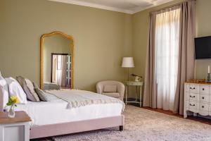 una camera da letto con un grande letto bianco e uno specchio di Villa Erbaia Relais de Charme a Barberino di Mugello