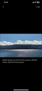 a picture of the ocean with the sky and clouds at Cabot Trail - Le Château Acadian in Chéticamp