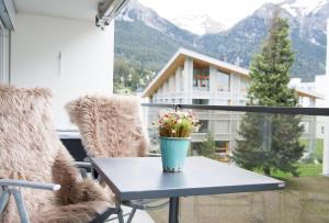 a table with flowers on a balcony with mountains at Stylish apartment with mountain view in Lenzerheide +4 photos