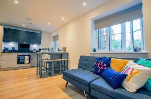 a living room with a blue couch and a kitchen at Guest Homes - Sedlescombe Apartment in Rugby