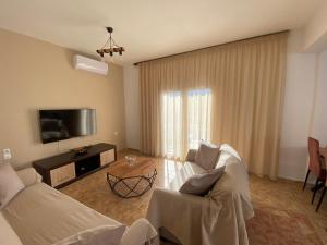 Una sala de estar con un sofá y un televisor. en VILLA LIA-SKIATHOS-PRIVATE POOL-, en Skiathos