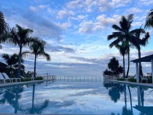 a swimming pool with palm trees and a view of the ocean at Tahiti Chalala2 in Aua