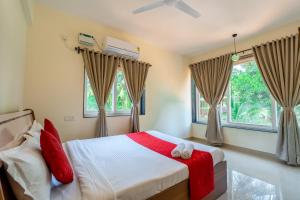 - une chambre avec un lit doté d'oreillers rouges et de fenêtres dans l'établissement Golden Sun Ray's Villas, à Baga