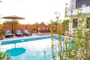 a swimming pool with two chairs and an umbrella at Kiteriders Garden Villas in Ulcinj