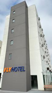 un gran edificio blanco con un cartel de hotel con mosca en Hotel Fly - Aeroporto Cuiabá en Várzea Grande