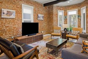 a living room with a brick wall and a flat screen tv at Highlands Square Bungalow - Private Yard - Garage in Denver