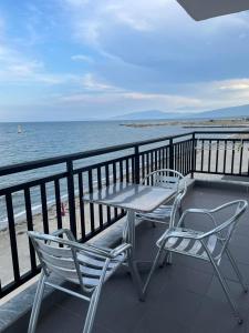 uma mesa e cadeiras numa varanda com vista para o oceano em Nepheli em Paralia Katerinis