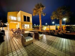 a patio with chairs and tables and palm trees at night at Profetas GuestHouse in Porto Santo