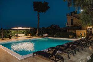 uma piscina à noite com cadeiras à volta em B&B Villa Seta em Agrigento