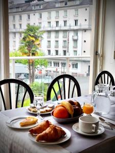 uma mesa com comida para o pequeno almoço com uma janela em HOTEL DE LISIEUX em Lourdes