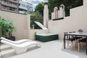 un patio con un banco blanco y una mesa en Fliphaus Chic Haus - 9 Lux Units 36 Pax en Buenos Aires